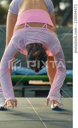 Athlete performs forward bend to loosen hamstrings outdoors 138094471