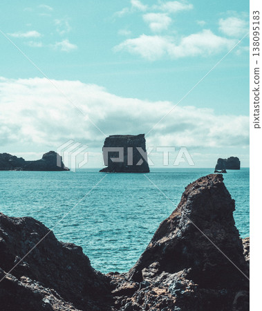 Dramatic seascape with rock formations at Dyrholaey, South Iceland, under a bright sky Dramatic seascape with rock formations at Dyrholaey, South Iceland, under a bright sky 138095183