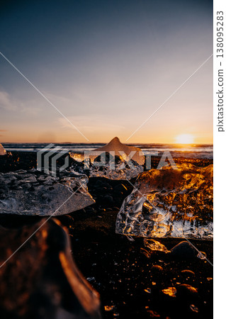 Glacial ice pieces glowing under golden sunset on Diamond Beach (Breidamerkursandur), Iceland. Glacial ice pieces glowing under golden sunset on Diamond Beach (Breidamerkursandur), Iceland. 138095283