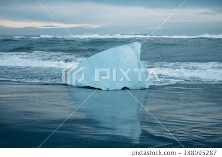 Large blue ice chunk on the black sand of Diamond Beach, South Iceland, at sunrise. Large blue ice chunk on the black sand of Diamond Beach, South Iceland, at sunrise. 138095287