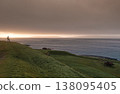 Solitary figure contemplates sunset over historical Torshavn coastline 138095405