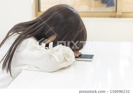 一名留著長髮的5歲日本女孩在使用智慧型手機時睡著了。 138096232