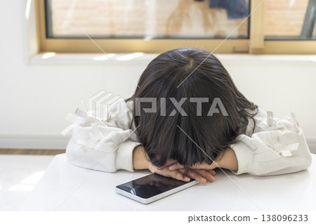 一名留著長髮的5歲日本女孩在使用智慧型手機時睡著了。 138096233