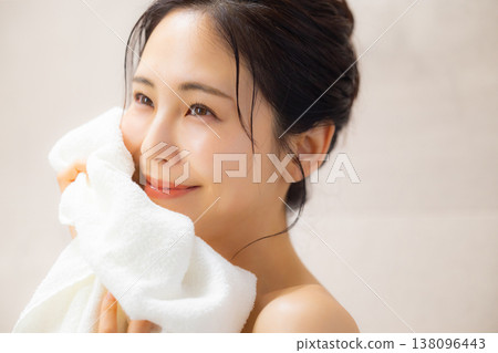 A young woman wiping her face with a towel after a bath. 138096443