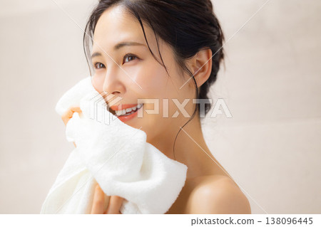 A young woman wiping her face with a towel after a bath. 138096445