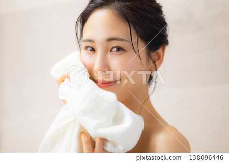 一位年輕女子洗完澡後用毛巾擦臉。 138096446