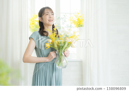 Woman arranging flowers on the windowsill Woman arranging flowers on the windowsill 138096809