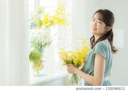 Woman arranging flowers on the windowsill 138096811