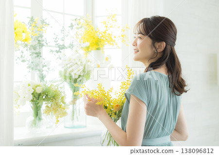 Woman arranging flowers on the windowsill 138096812