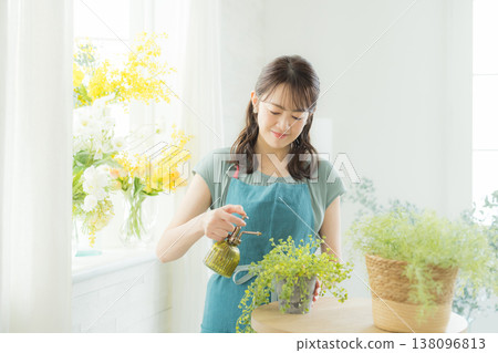 Woman arranging flowers on the windowsill 138096813