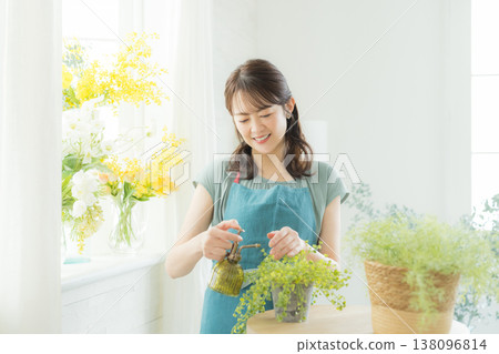 女子在窗台上插花。 女子在窗台上插花。 138096814