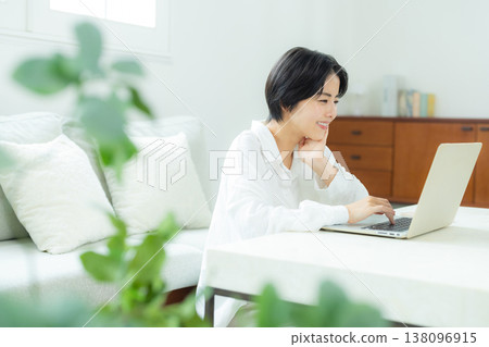 A woman watching a computer at home 138096915