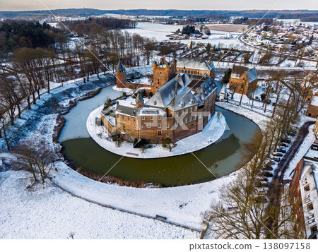 Detailed aerial view of Huis Bergh Castle in winter. Historical medieval brick fortress surrounded by a frozen circular moat and snow covered grounds in a picturesque European town landscape. Detailed aerial view of Huis Bergh Castle in winter. Historical medieval brick fortress surrounded by a frozen circular moat and snow covered grounds in a picturesque European town landscape. 138097158