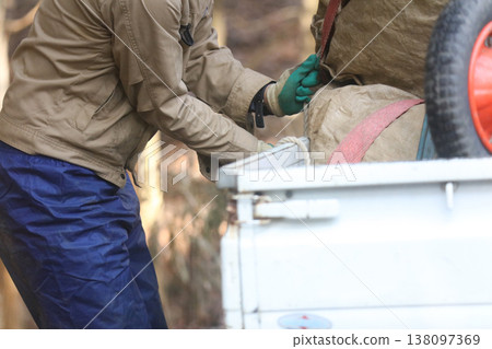 A man loading collected leaves onto a light truck A man loading collected leaves onto a light truck 138097369
