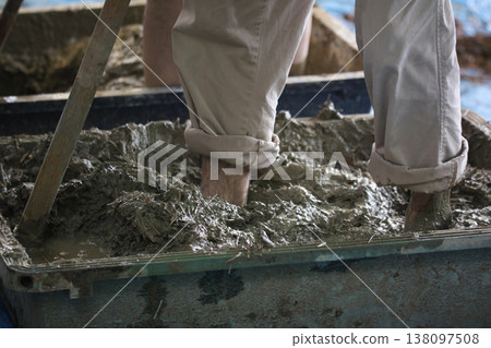 A man making rough wall soil by stepping on it A man making rough wall soil by stepping on it 138097508
