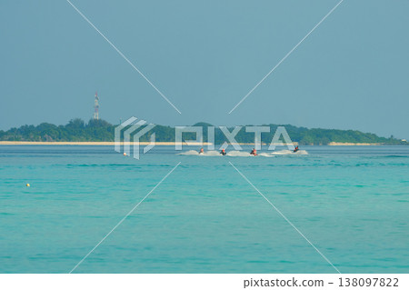 A group of young people have fun on jet skis during a vacation in the Maldives at sunset 138097822