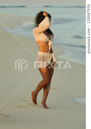 A beautiful tanned girl in a swimsuit runs along a white beach at sunset in the Maldives, she is happy, posing for a photographer 138097938