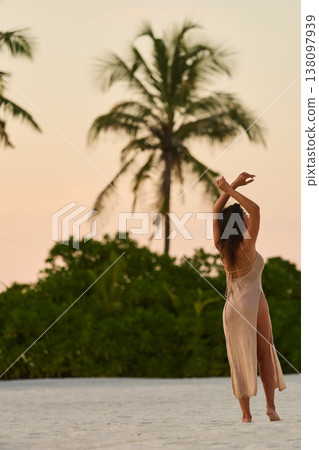 A beautiful tanned girl in a swimsuit runs along a white beach at sunset in the Maldives, she is happy, posing for a photographer A beautiful tanned girl in a swimsuit runs along a white beach at sunset in the Maldives, she is happy, posing for a photographer 138097939