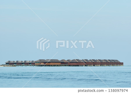 Classic Maldives island landscape on a sunny day, coastal luxury resort buildings, azure water, white sand, palm trees on the shore Classic Maldives island landscape on a sunny day, coastal luxury resort buildings, azure water, white sand, palm trees on the shore 138097974