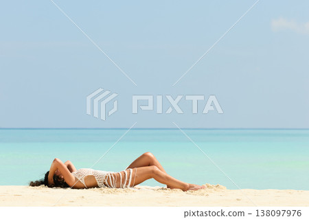 A beautiful tanned girl with an athletic physique in a swimsuit is lying on the beach on a sunny day in the Maldives, she is happy and posing A beautiful tanned girl with an athletic physique in a swimsuit is lying on the beach on a sunny day in the Maldives, she is happy and posing 138097976