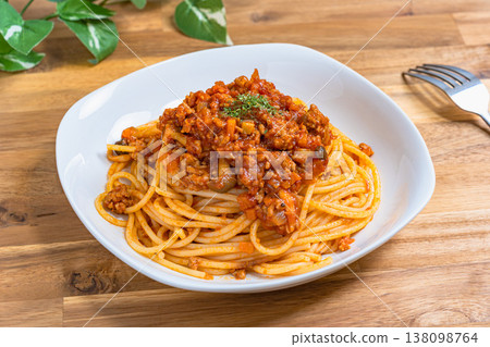 肉醬義大利麵（博洛尼亞肉醬）盛在白色盤子裡，配上木桌，營造出西式用餐氛圍。 138098764