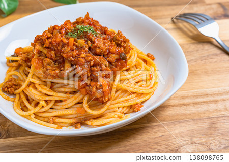 Meat sauce pasta, Bolognese served on a white plate, with a wooden table creating a Western-style dining image. Meat sauce pasta, Bolognese served on a white plate, with a wooden table creating a Western-style dining image. 138098765