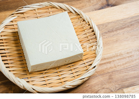 Cotton tofu on a sieve; Japanese food ingredients on a wooden table. 138098785