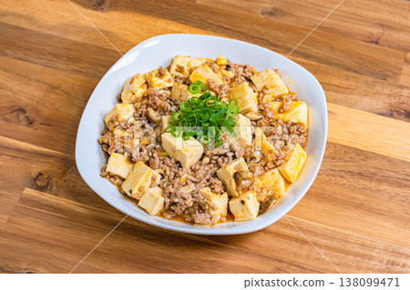 Mapo Tofu, Chinese food served on a white plate, home-style cooking on a wooden table. Mapo Tofu, Chinese food served on a white plate, home-style cooking on a wooden table. 138099471