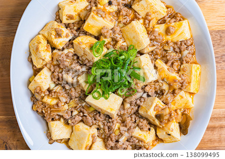 Mapo Tofu, Chinese food served on a white plate, home-style cooking on a wooden table. 138099495