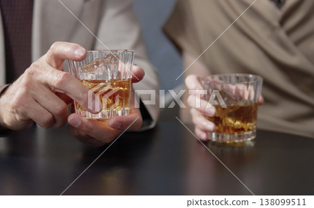 特寫鏡頭：一位老年男子和一位老年女子正在喝威士忌，他們的手在鏡頭前。 138099511