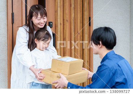 A girl receiving a package and her mother A girl receiving a package and her mother 138099727