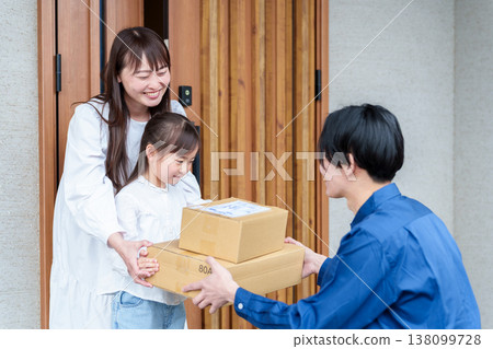 A girl receiving a package and her mother A girl receiving a package and her mother 138099728