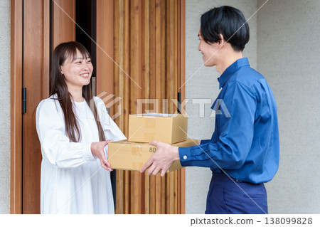 一位女士從快遞員手中接過包裹 一位女士從快遞員手中接過包裹 138099828