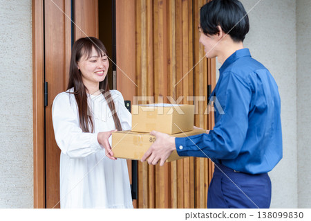 A woman receiving a package from a delivery person 138099830