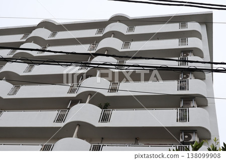 Low-rise buildings in a residential area and rows of cherry trees create a peaceful spring scene. 138099908