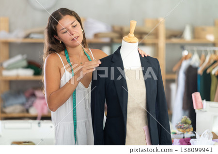 Female tailor fitting black blazer on mannequin Female tailor fitting black blazer on mannequin 138099941