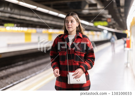 Girl is standing on subway platform, waiting for train to arrive Girl is standing on subway platform, waiting for train to arrive 138100033