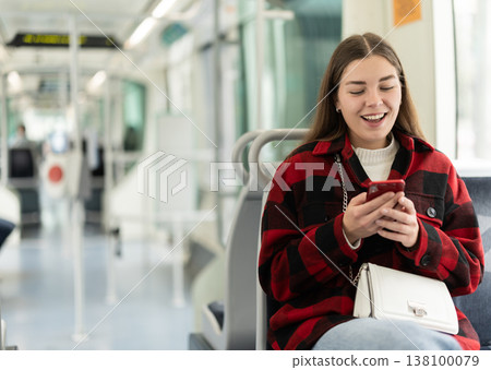 Woman sitting in tram car with phone Woman sitting in tram car with phone 138100079