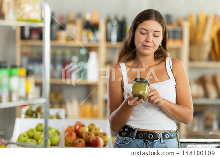Young woman choosing green peas in grocery store 138100109