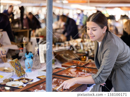 Young woman chooses vintage jewelry at flea market Young woman chooses vintage jewelry at flea market 138100171