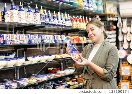 Happy female tourist looking to buy ornamental spoon rests at gift shop Happy female tourist looking to buy ornamental spoon rests at gift shop 138100174