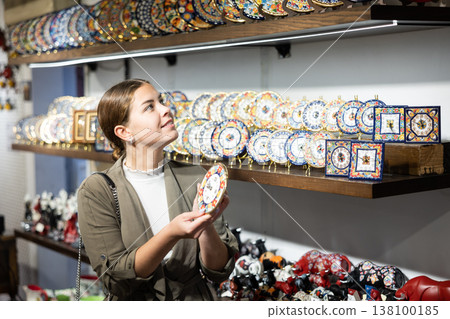 Young woman chooses decorative clock at souvenir market 138100185