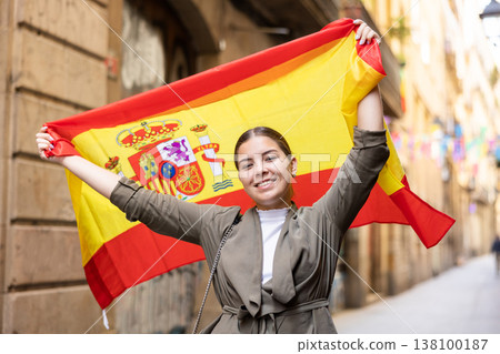 Happy young woman waving the flag of Spain on city street Happy young woman waving the flag of Spain on city street 138100187