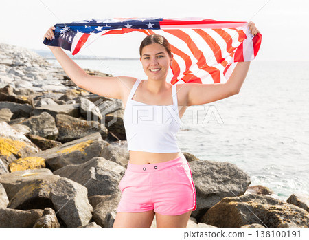Young woman on coast posing with flag of USA 138100191