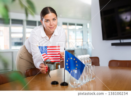 Preparing for business presentation - secretary places flags of European Union and USA on negotiating table Preparing for business presentation - secretary places flags of European Union and USA on negotiating table 138100234