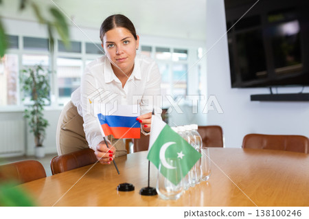 Young woman puts flags of Russia and Pakistan on table in office Young woman puts flags of Russia and Pakistan on table in office 138100246