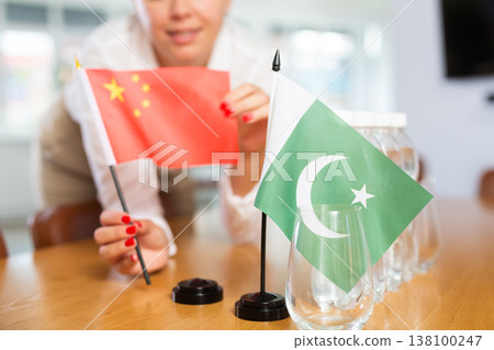 Little flag of Pakistan on table and flag of China put next to it by young woman Little flag of Pakistan on table and flag of China put next to it by young woman 138100247