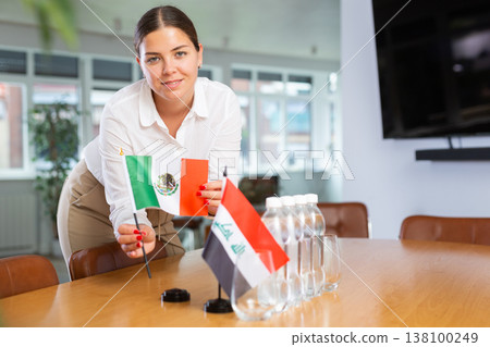 Young lady sets miniatures flags of Iraq and Mexico for international negotiations 138100249