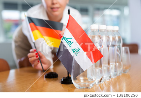 Unrecognizable girl sets midget flags of Iraq and Germany before international negotiations Unrecognizable girl sets midget flags of Iraq and Germany before international negotiations 138100250