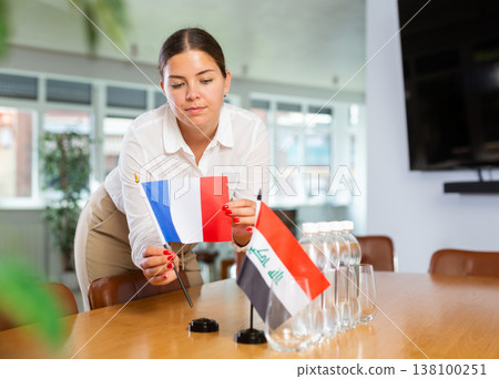 Woman secretary prepares the negotiating table - arranges flags of France and Iraq 138100251